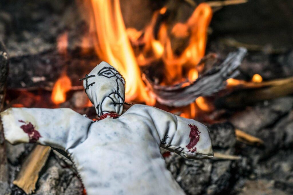 A white voodoo doll in front of a fire. Is black magic real.